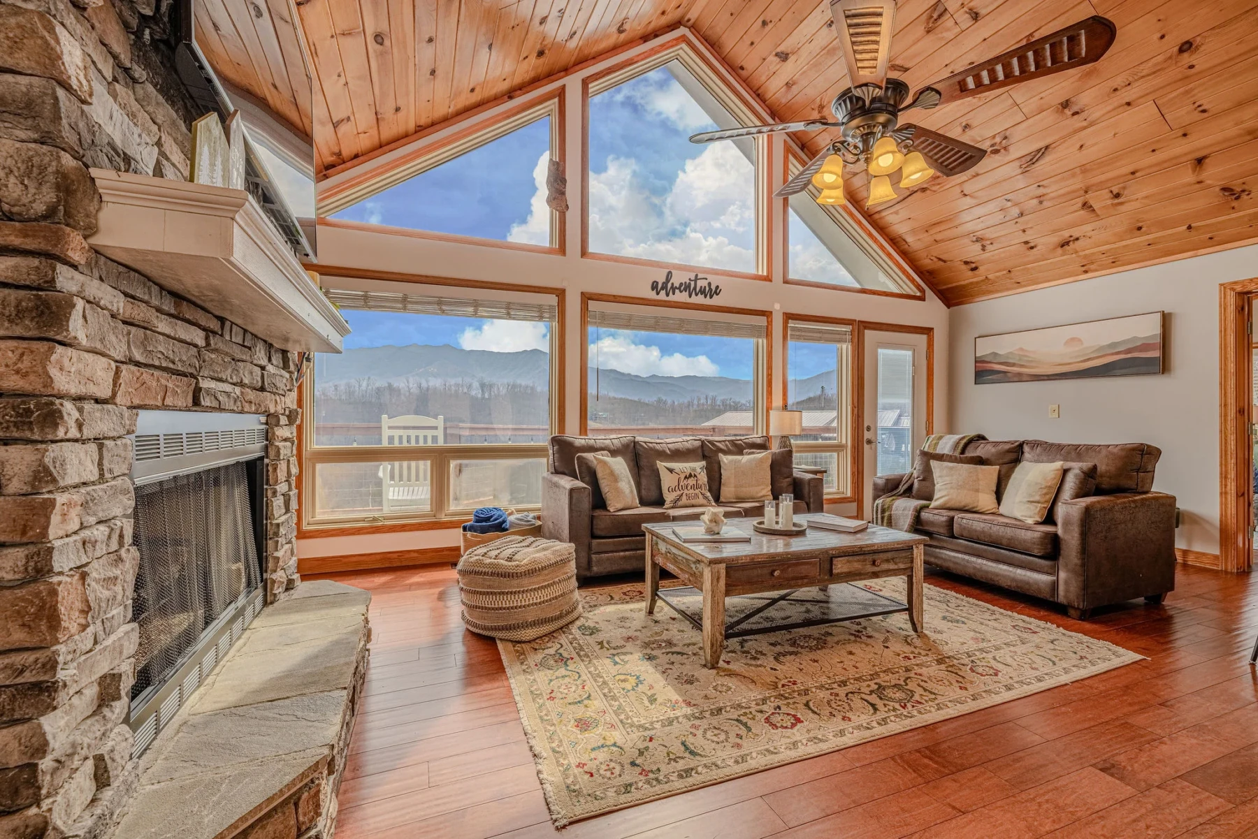 Luxury mountain view living room with vaulted ceilings, stone fireplace and panoramic windows at Summit View Lodge near