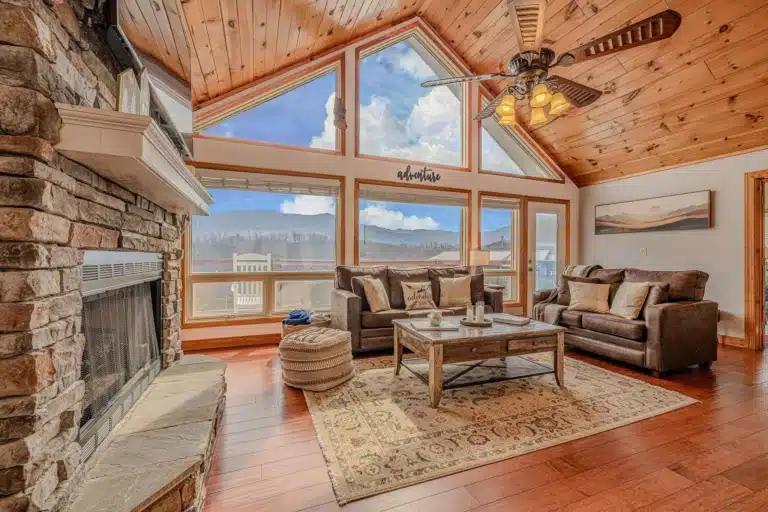 Modern living room with stone fireplace and mountain views at Summit View Lodge