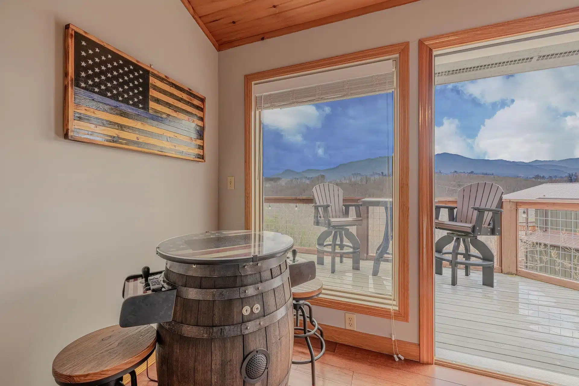 Rustic bar with whiskey barrel high-top table and wood bar stools by windows overlooking mountain views, a Gatlinburg cabin