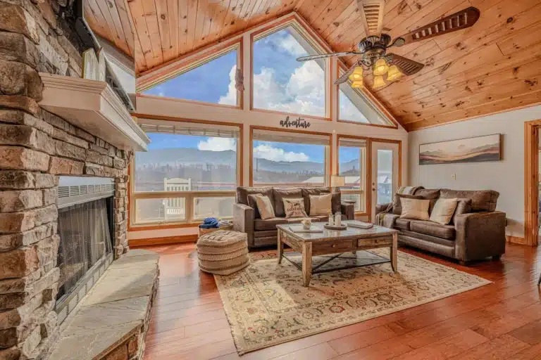 Luxury living room with vaulted wood ceiling, stone fireplace, and mountain view windows at our Gatlinburg long weekend trip